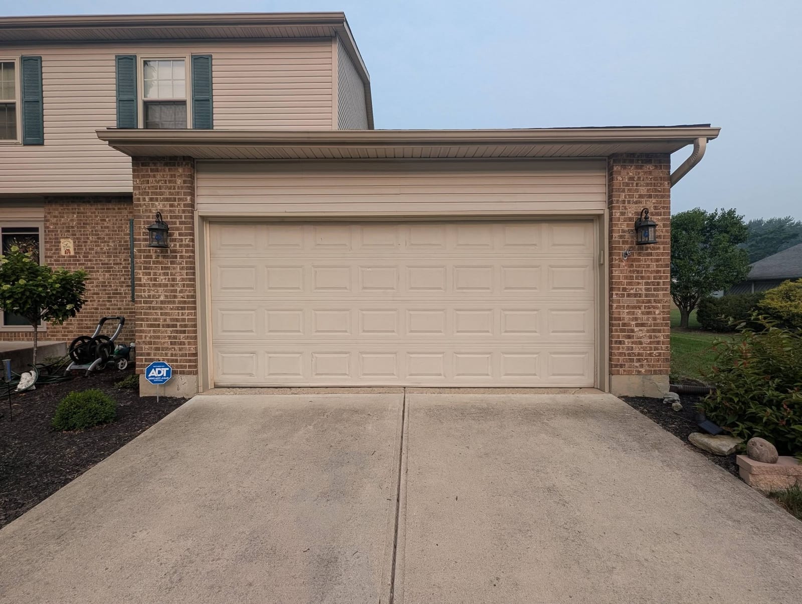 Plain cream garage door on a brick home before replacement