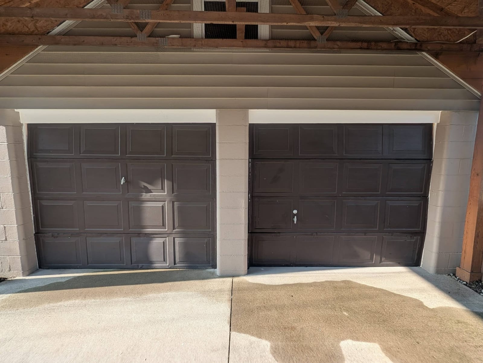 Two brown garage doors with visible dents before replacement