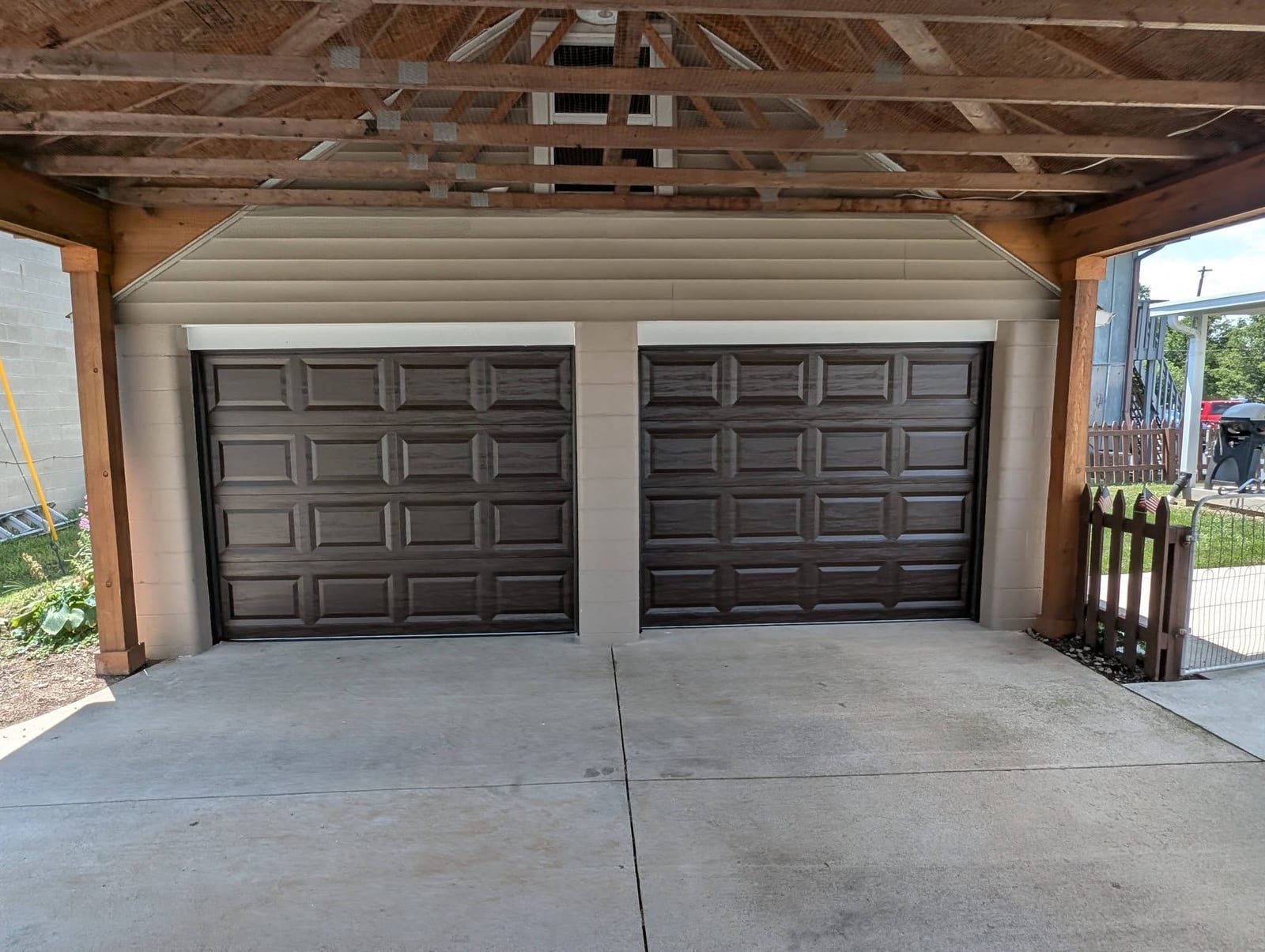 Two finished brown raised-panel doors under the same covered structure