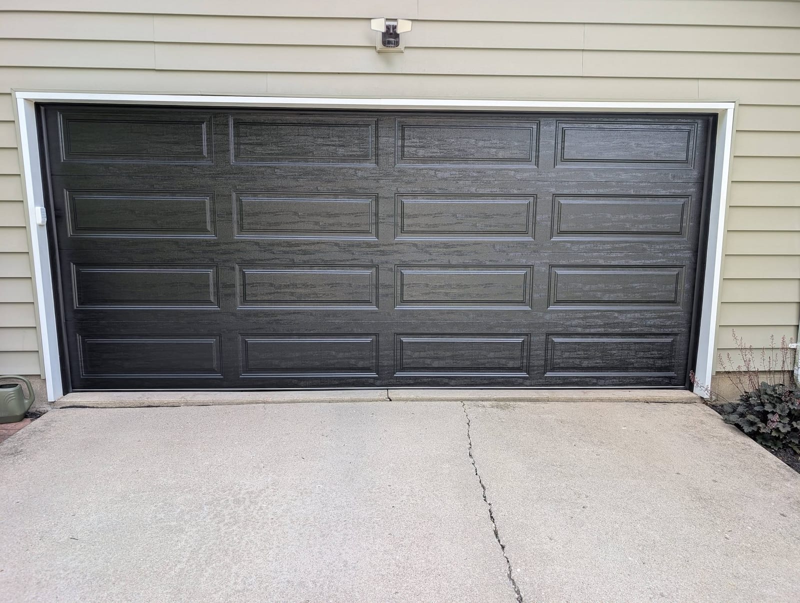 Black raised-panel door installed on the same light-sided garage