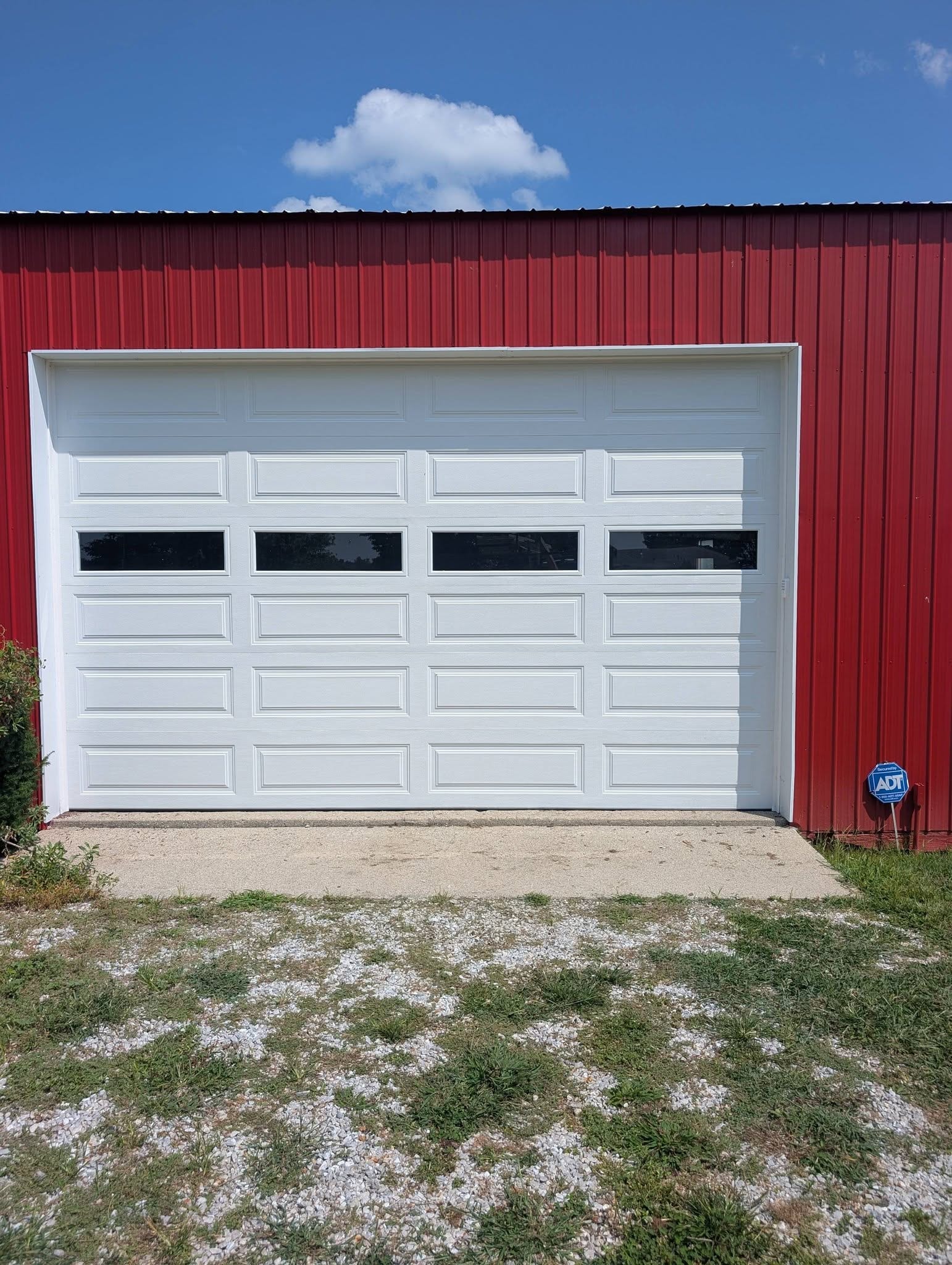 New white garage door with windows on the same red barn