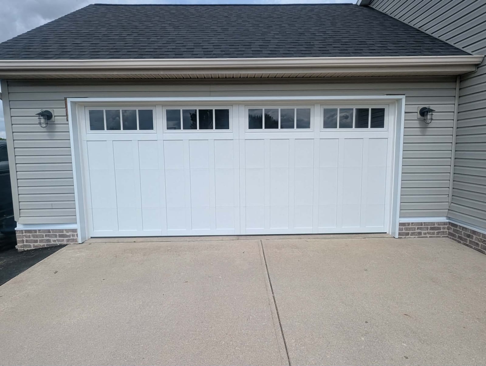 White carriage-style garage door with a row of windows on the same gray-sided garage
