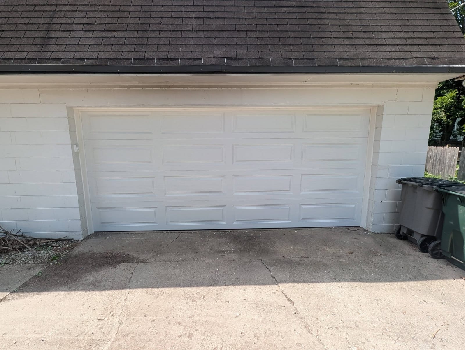 New white raised-panel garage door on the same white garage